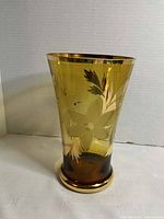 Side view of amber smoked glass vase showing etched floral design and gilding