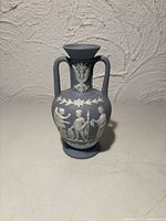 front view showing blue vase with white relief figures and handles