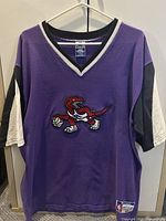 Front view of Champion Toronto Raptors shooting shirt showing logo and jock tag