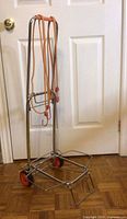 Full view of folding chrome trolley cart with bungee cords draped over handle