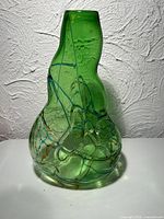 Front view of green art glass vase showing amber and blue trailing