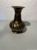 Front view of brass vase showing fluted body and flared rim
