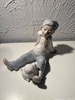 Full view of figurine boy seated with dog