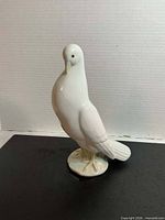 Front angled view of white porcelain dove on base