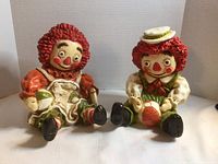 Front view of both seated Girotti Raggedy Ann and Andy ceramic figurines