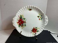 Front view of platter showing poinsettia pattern and gold-trimmed scalloped rim