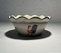 Bowl side view showing rooster graphic and scalloped rim