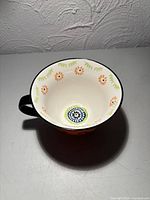 Interior view of mug showing cream background with orange flowers and green leaves