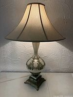 Full view of lit lamp showing shade shape and base