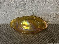 Top view of oval marigold carnival glass tray showing iridescence and pattern