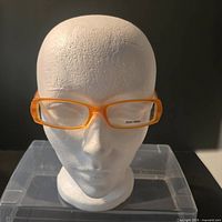 Front view of orange Miu Miu eyeglass frames on mannequin head