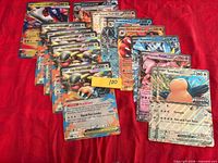 Front view of stacked jumbo Pokémon cards on red fabric showing variety