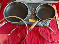 Both pans, both lids, and grey sleeve displayed on table