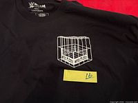 Front of shirt showing small cage ring graphic and printed neck label