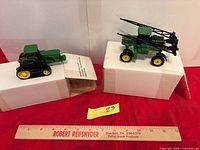 Both toy tractors on boxes with ruler for scale