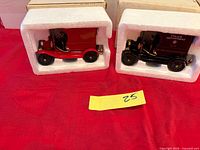 Red and black die-cast delivery truck models in styrofoam