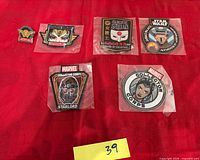 Six sealed embroidered patches laid out on red surface