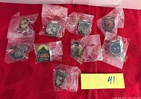 Overview of ten sealed enamel pins on red background