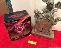 Boxed Stranger Things Demogorgon inflatable beside Beetlejuice tombstone figure