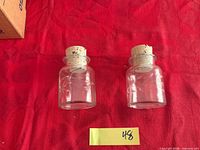 Two etched glass spice jars with corks displayed