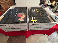 Two bankers boxes filled with rows of black slim DVD cases