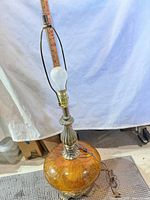 Full view of lamp showing crackle glass base, metal neck, harp and bulb for scale