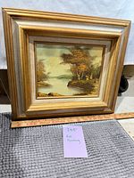 Full view of framed fall landscape painting with measuring stick