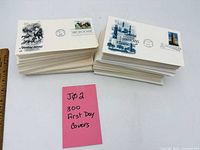 Two stacks of first day covers, ruler for scale, pink note indicating 300 covers