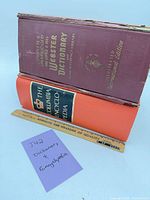 Both books standing, showing detached cover of Webster dictionary and spine of Columbia encyclopedia with ruler for scale