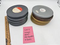 Stacks of metal film canisters showing colors and labels next to ruler and note card