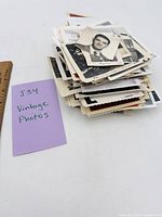 Stack of vintage photos next to ruler and note card