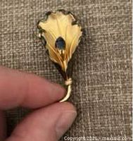 Front view of gold-tone sterling leaf brooch with blue stone