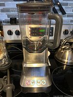 Full blender assembled on stovetop with additional cup and accessories visible