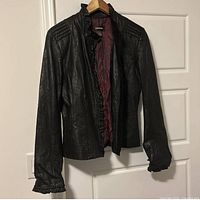Front view of black leather jacket hanging on door