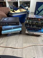 Two stacks of books showing spines including War Storm, King's Cage, Glass Sword, Red Queen, The Chemist and Lana Harper titles