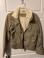 Front view of khaki Guess jacket on hanger