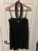 Full front view of black embellished halter mini dress on hanger