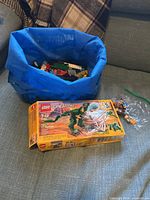 Boxed LEGO Creator Mighty Dinosaurs set, zip bag of minifigures, tote with loose bricks