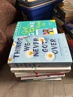 Stack of paperback romance novels; top title Things We Never Got Over; Girl Gone Viral visible on bin