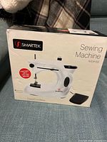 Front of retail box showing Smartek sewing machine and pedal