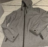 Full view of grey hooded jacket laid flat showing front, zip pockets, cuffs