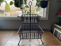 Front view of black two-tier wire basket stand on tabletop