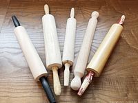 Five wooden rolling pins on table, handles up