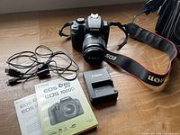 Complete kit laid out showing camera with lens, neck strap, charger, USB cable, pocket guide