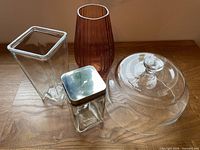 Group shot of all four glass items: cloche, both vases, canister