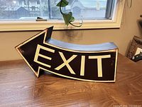 Front view of painted metal EXIT arrow sign on table