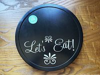 Top view of black wooden lazy Susan with "Let's Eat!" text