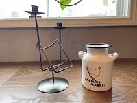 Metal candle and wine bottle holder beside white enamel mini milk can