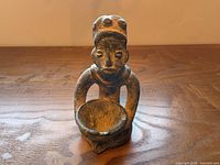 Front view of terracotta figurine holding bowl