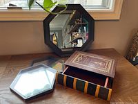 Two octagonal mirrors and faux book storage box displayed on table